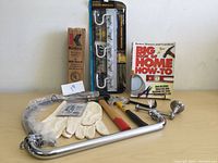 Wide shot showing all items in the lot including fire extinguisher box, storage rack package, tools, gloves, and how-to book.