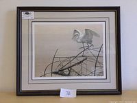 Full view of framed print showing bird perched on branches over water in neutral colors with a dark frame and matting.