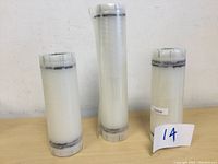 Photo of three tightly rolled FoodSaver vacuum sealer refill rolls on a light wood surface against a white wall.