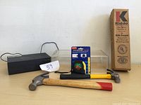 Photo of two hammers, tape measure, boxed fire extinguisher and black rectangular Bluetooth alarm clock