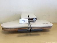 Top angled view of white ironing press closed showing front with handle and control dial.