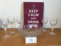 Front view of five crystal glasses in two sizes, crystal fruit bowl, and wall plaque with text.