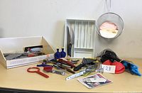 Photo showing assortment of kitchen utensils including knives, a box for utensils, and mesh strainer