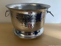 Front and side view of hammered aluminum planter showing hammered texture, flared rim, and side rings.