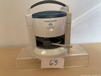 Front view of the Black & Decker Lids Off jar opener showing the handle, brand logo, and opening for jars.