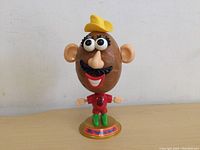 Front view of the Mr Potato Head toy figure showing detailed facial features and colorful base.