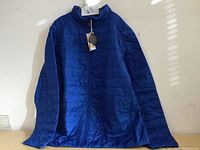 Front view of the blue men's XXL CORE 365 ski jacket with tags hanging from the collar, showing zipper and quilted pattern.