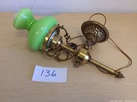 View of vintage brass wall sconce showing green glass globe and ornate brass mounting hardware.