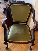 Front view of antique Queen Anne style armchair showing green fabric upholstery and solid walnut carved frame.