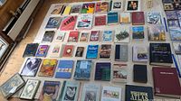 Photo showing a wide assortment of books laid out on a flat surface, including various sizes and types.
