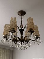 Full view of chandelier hanging from ceiling showing five amber glass shades and crystal accents.