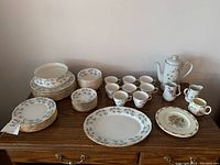Full view of Queen Anne china set arranged on table with plates, bowls, cups, coffee pot and creamers