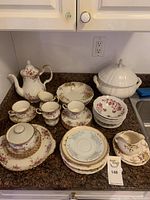 Full overview photo showing tea pot, cups and saucers, dessert plates, vegetable pot, and sugar bowl arranged on kitchen counter.