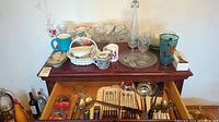 Overview of assorted dishware and cutlery displayed on cabinet and in drawer