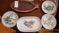 Overview of ceramic fish platter and five porcelain fish-design plates on a table