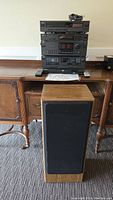 Photo of full stereo system stacked on wood furniture with wooden speaker in front.