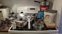 Full view of kitchenware items including pots, glass dishes, kitchen scale, and boxed Black & Decker item on stovetop