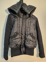 Front view of the black Atmosphere women's winter jacket showing padded front, pockets, knit sleeves and ribbed hem.