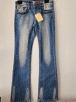 Full front view of women's stretch denim pants showing distressing on thighs and faded effect