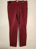 Full front view of maroon dressy pants clipped and hung, showing entire pant length with belt loops and waistband.