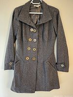 Front view of the dark grey Lovestitch women's long winter jacket hanging on a hanger, showing double-breasted button design, lapel collar, and front pockets.