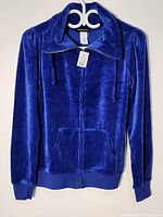 Front view of blue velvet blazer showing collar, zip closure, and pockets.