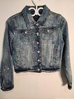 Full view of blue denim jacket front showing button front closure, two button flap chest pockets, and side pockets