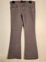 Full view of the light grey women's denim pants hanging, showing front with decorative stitching details on right pocket and overall shape.