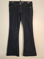 Full view of black denim stretch pants showing front, waist, pockets, and full length with flare