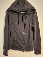 Front view of the black Seductions women's hoodie showing button details, pockets, and hood.