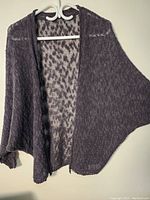 Full view of dark grey wool knit women's sweater hanging, showing open front and relaxed fit.