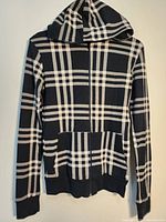 Front view of black and white plaid hoodie with hood and front zipper.