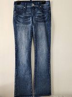 Full front view of blue denim stretch pants, showing front pockets, button closure, and straight leg cut.