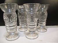 Four clear Mondae Siren glasses shown from front angle showing embossed circular and horizontal patterns on the glass body.