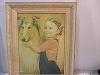 Front view of the framed embossed art showing a young girl holding a dog.