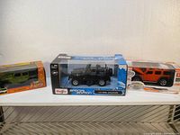 Three boxed Jeep die cast model cars from Maisto, Burago, and Super Diecast brands displayed together