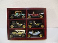 Photo of six vintage style die-cast toy cars arranged in a wooden display case with six compartments.