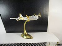 Front angled view showing the white airplane sculpture mounted on the gold-tone metal stand with three gold propellers visible.