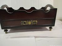 Side view of wooden wine bottle holder with brass decorative plate and feet