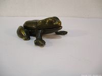 Side angle view of the brass frog trinket box depicting detailed frog features and the hinge area where the box opens.