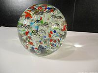 Side view showing the clear glass paper weight with embedded multicolor spots and multiple internal air bubbles