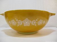 Side profile view showing yellow exterior with white floral pattern and handles on each side.