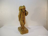 Full front view of the wood carving showing the figure standing on a base.