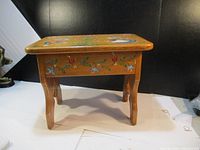 Side view of wooden stool showing tole painted sides and legs.