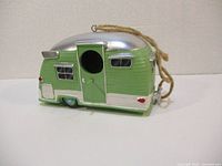Front side of green and silver trailer bird house showing round entrance hole and details