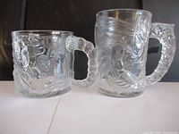 Two clear embossed glass mugs showing intricate Batman and Two-Face characters from 1995, photographed from the front.