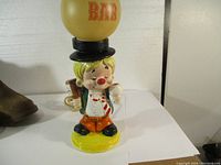 Full view of the vintage clown bar lamp showing the figurine holding drinks with the round yellow 'BAR' lampshade above.