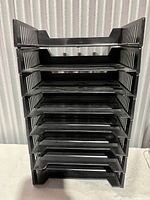 Front view of the black plastic paper trays stacked vertically showing all 8 levels.