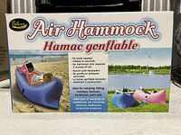 Front view of Relaxx Air Hammock box showing product image on beach and grassy field, highlighting portability and ease of inflation with no tools needed.
