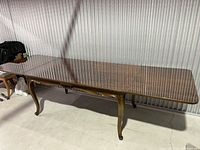 Image of Hungarian walnut dining table in extended position showing rectangular top, curved legs with slight sun bleaching, and polished finish.